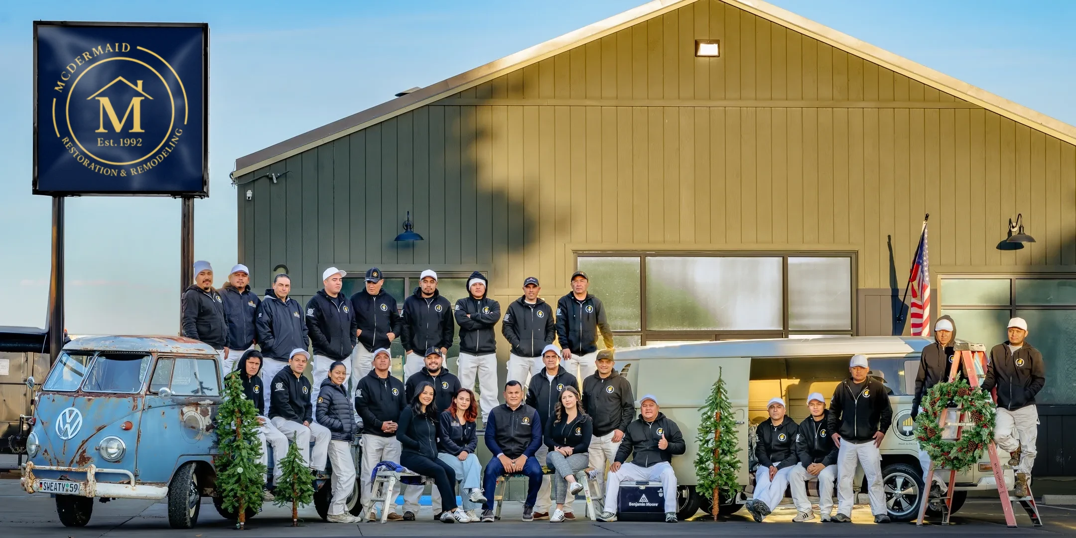 The McDermaid team gathered in front of the company shop and its McDermaid sign, with two vintage VW buses