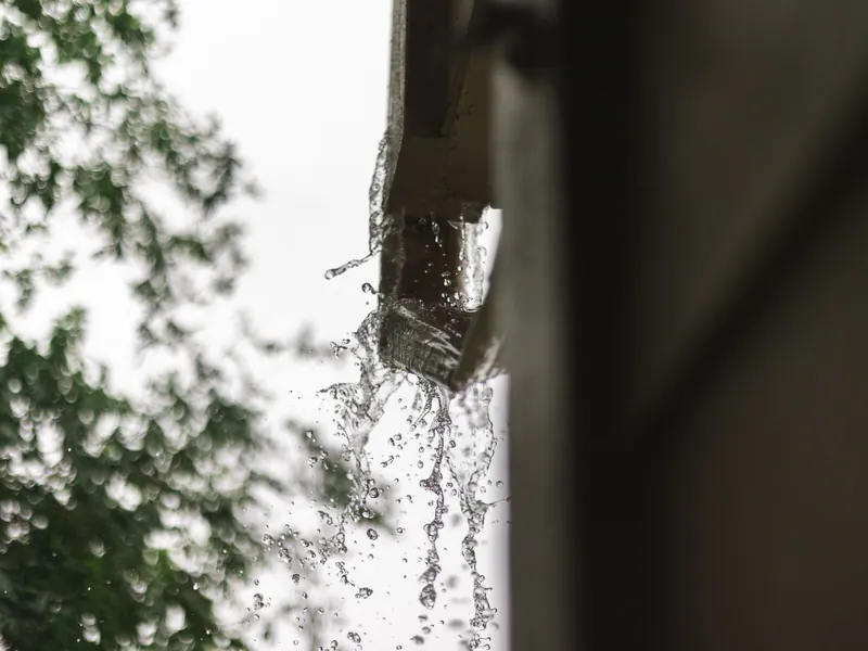 Rain pouring from the end of a gutter