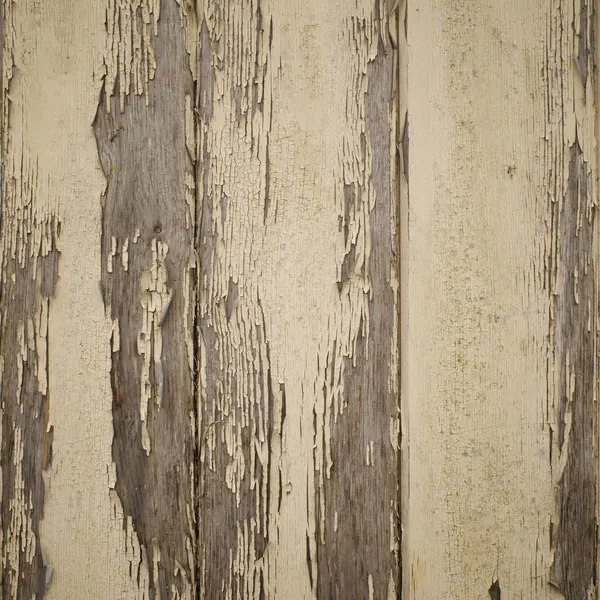 Cream paint peeling off weathered wood boards