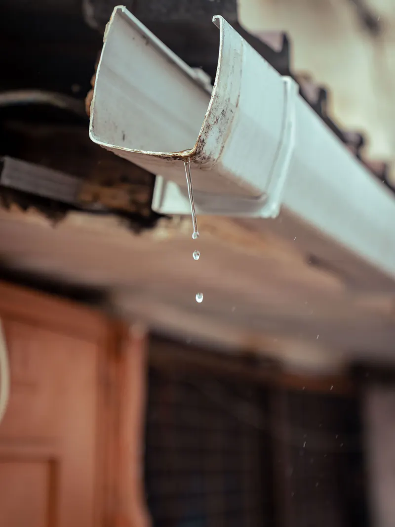 Water dripping from the end of a white gutter
