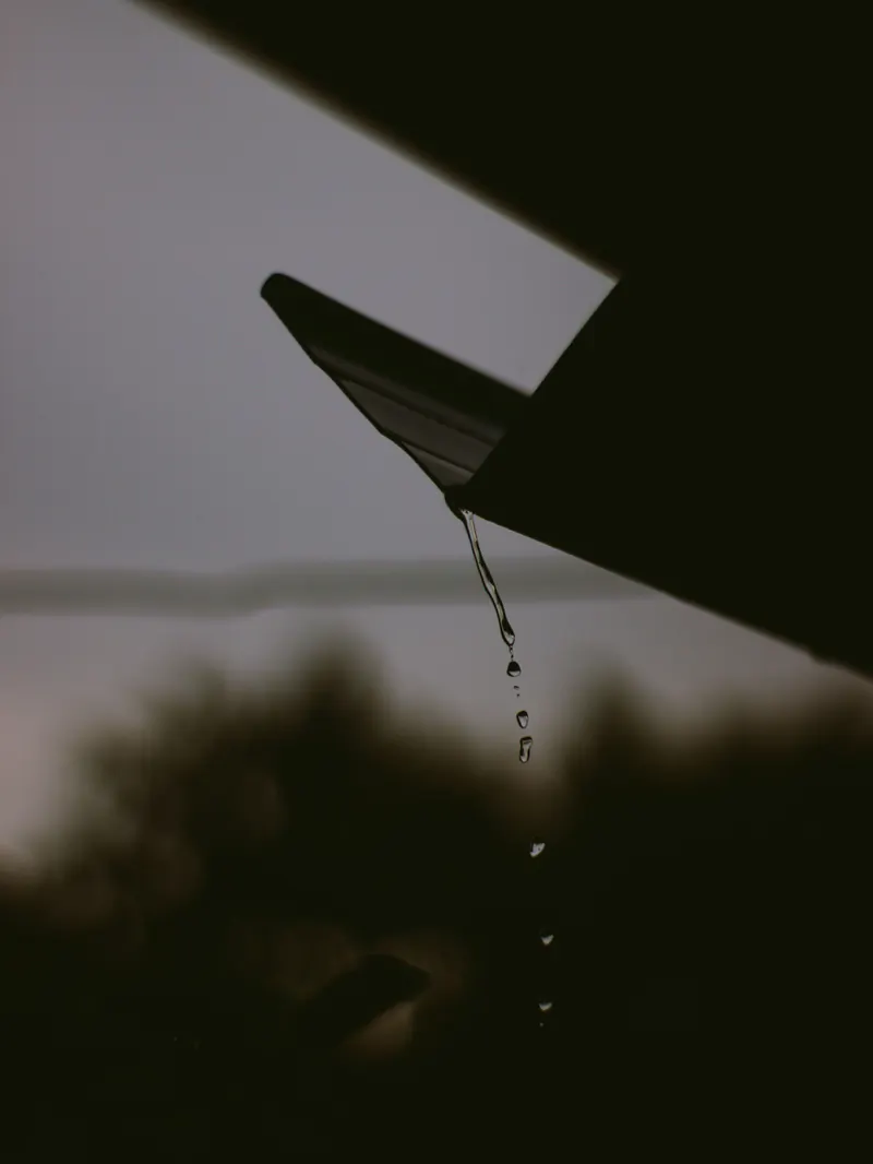 Rain running off a dark roof edge at dusk