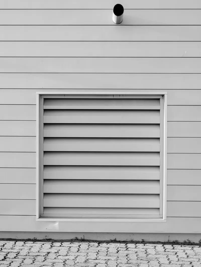 A louvered vent in gray lap siding