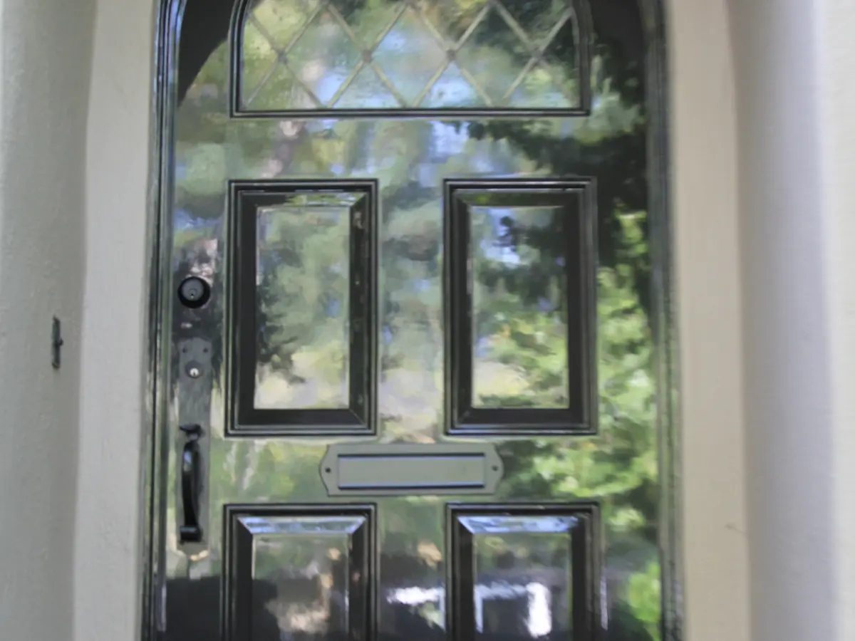 A black high-gloss front door with leaded glass panels