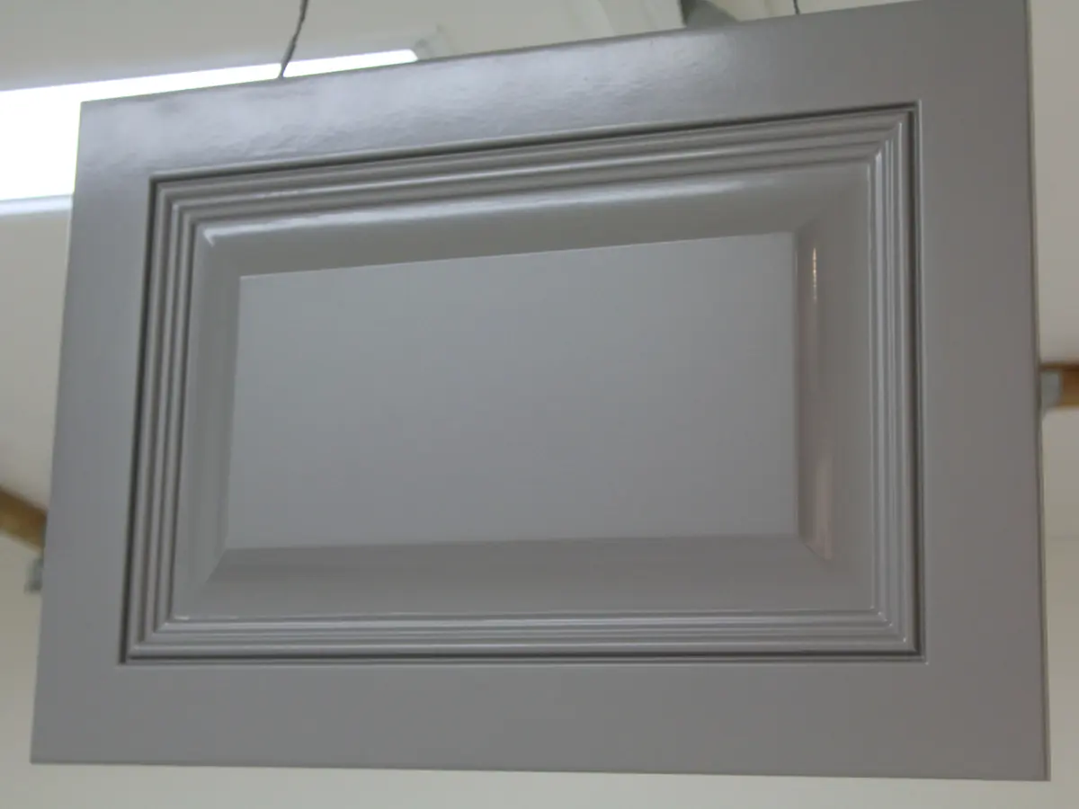 A grey raised-panel cabinet door with a smooth sprayed finish