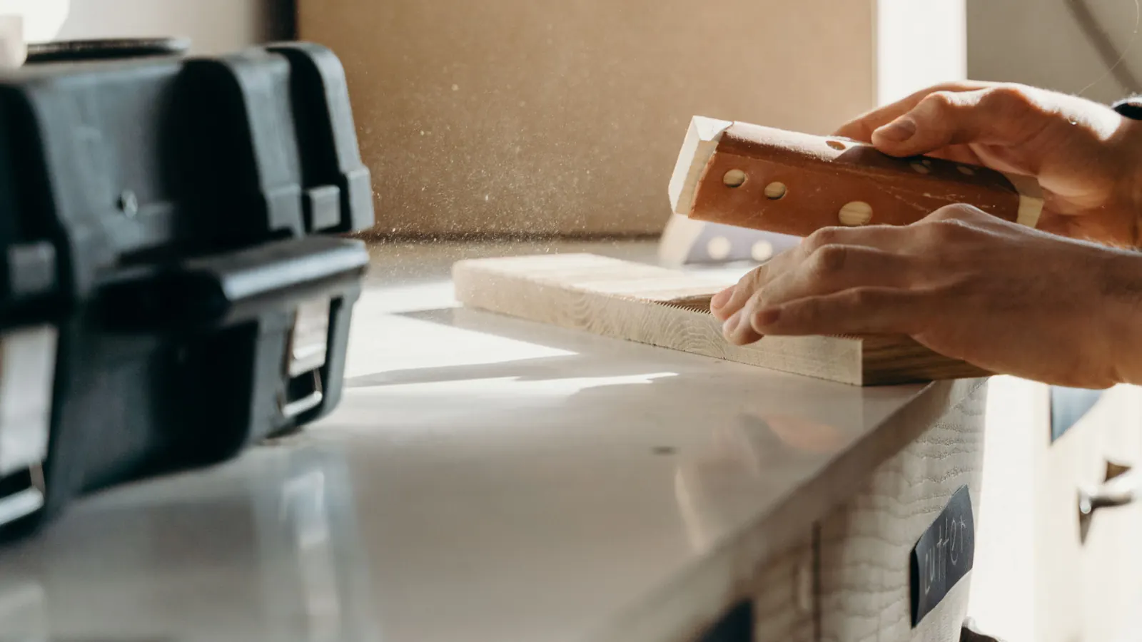 Hands sanding a board with a sanding block