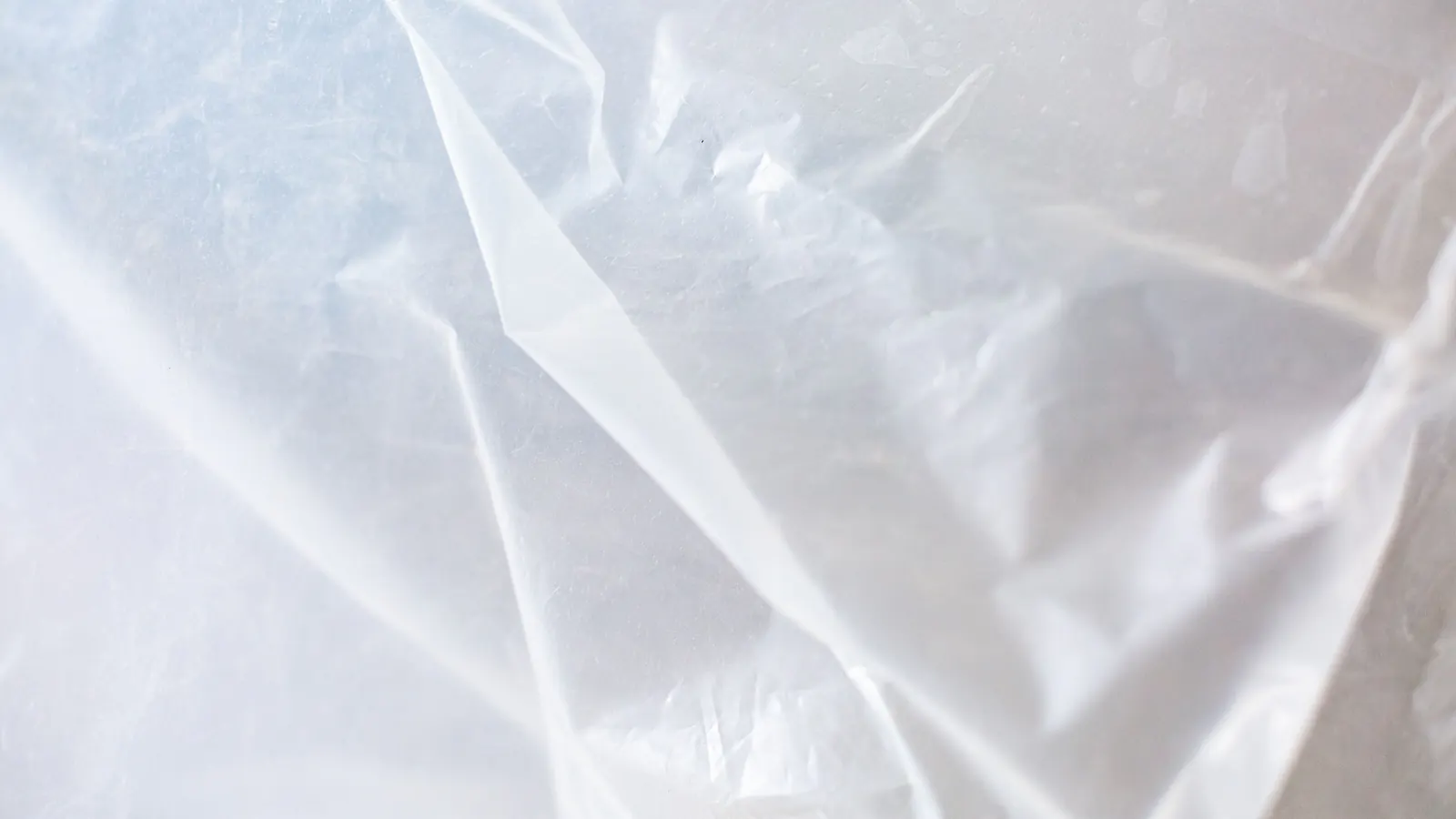 A close view of clear plastic sheeting laid in loose folds, the kind used to cover a work area.
