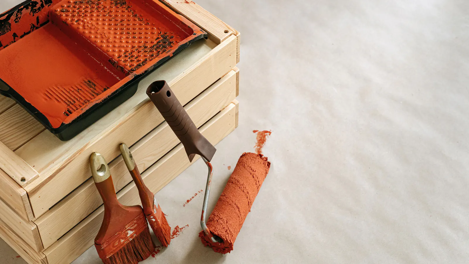 Brushes, a roller and a paint tray with fresh orange paint