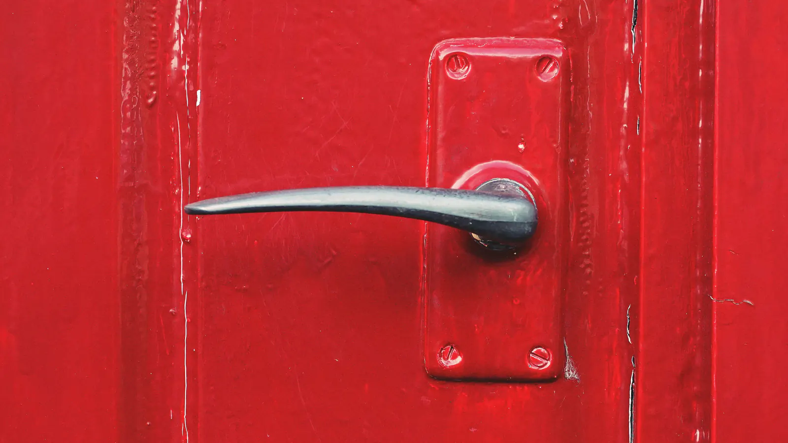 A glossy red painted door with a silver lever handle