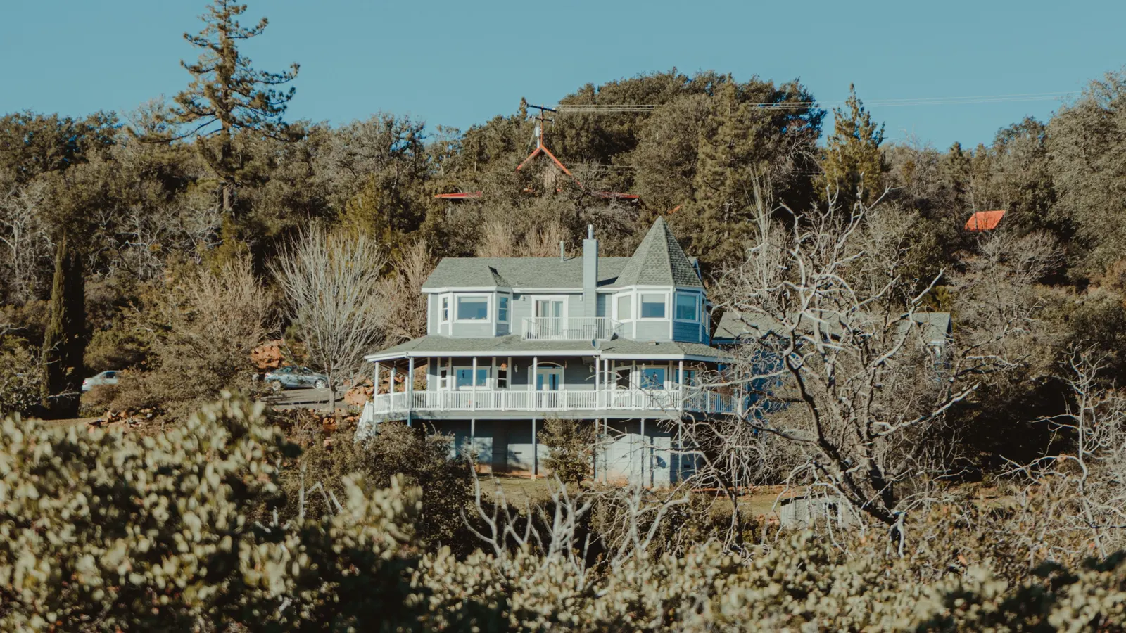 A house on a wooded hillside among dry brush