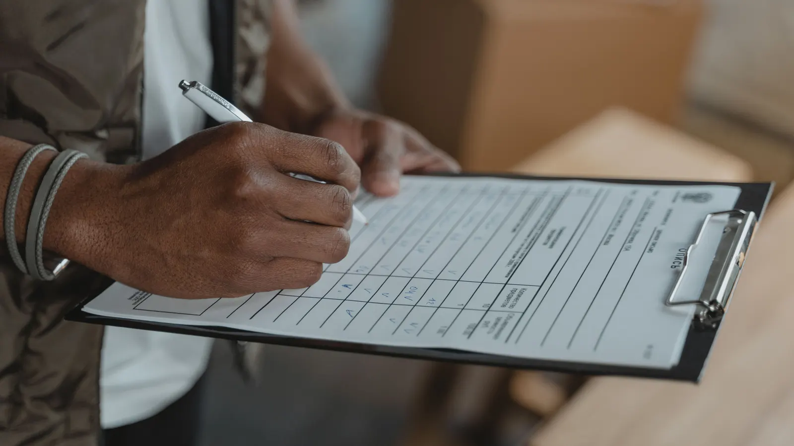 A hand filling in a form on a clipboard