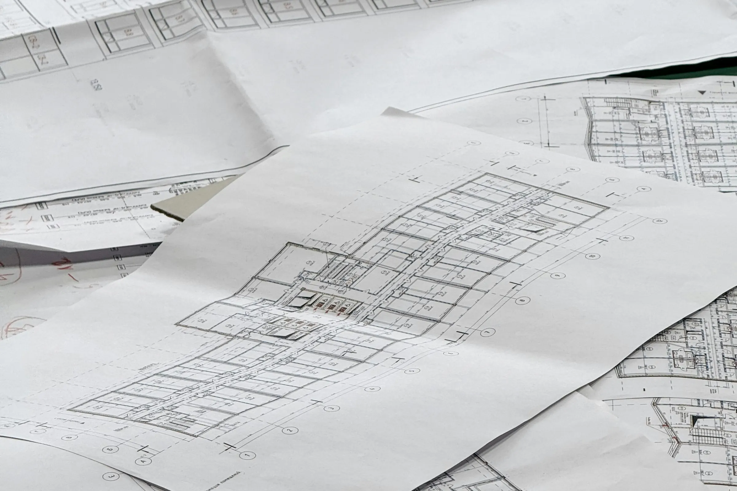 Layers of architectural plan sheets spread out in soft grey light