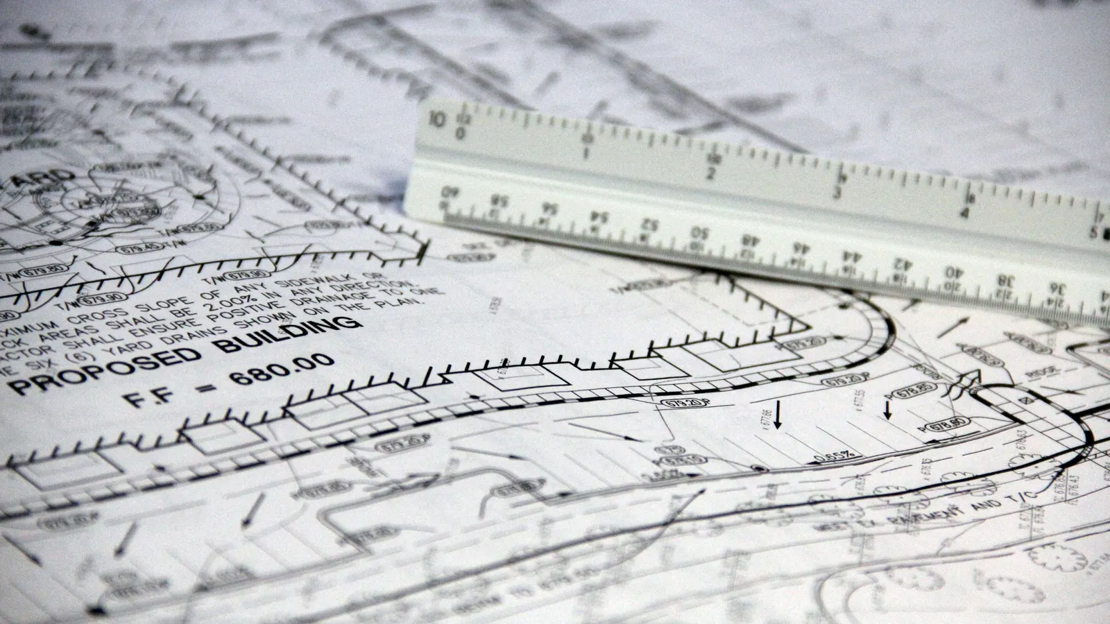 A white architect’s scale ruler resting on a printed site plan