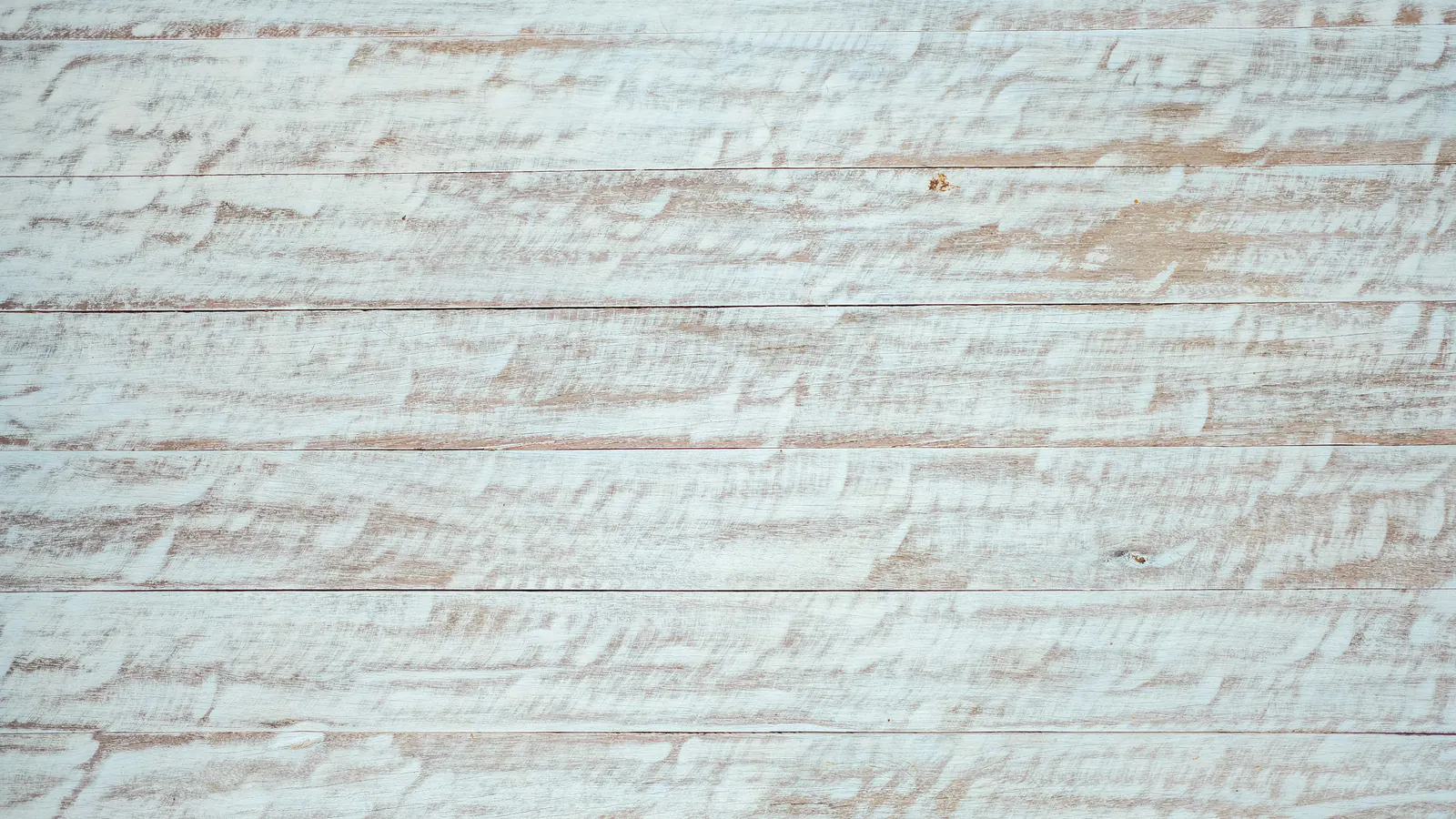 Close view of horizontal wood boards with a thin white coat brushed over the bare grain