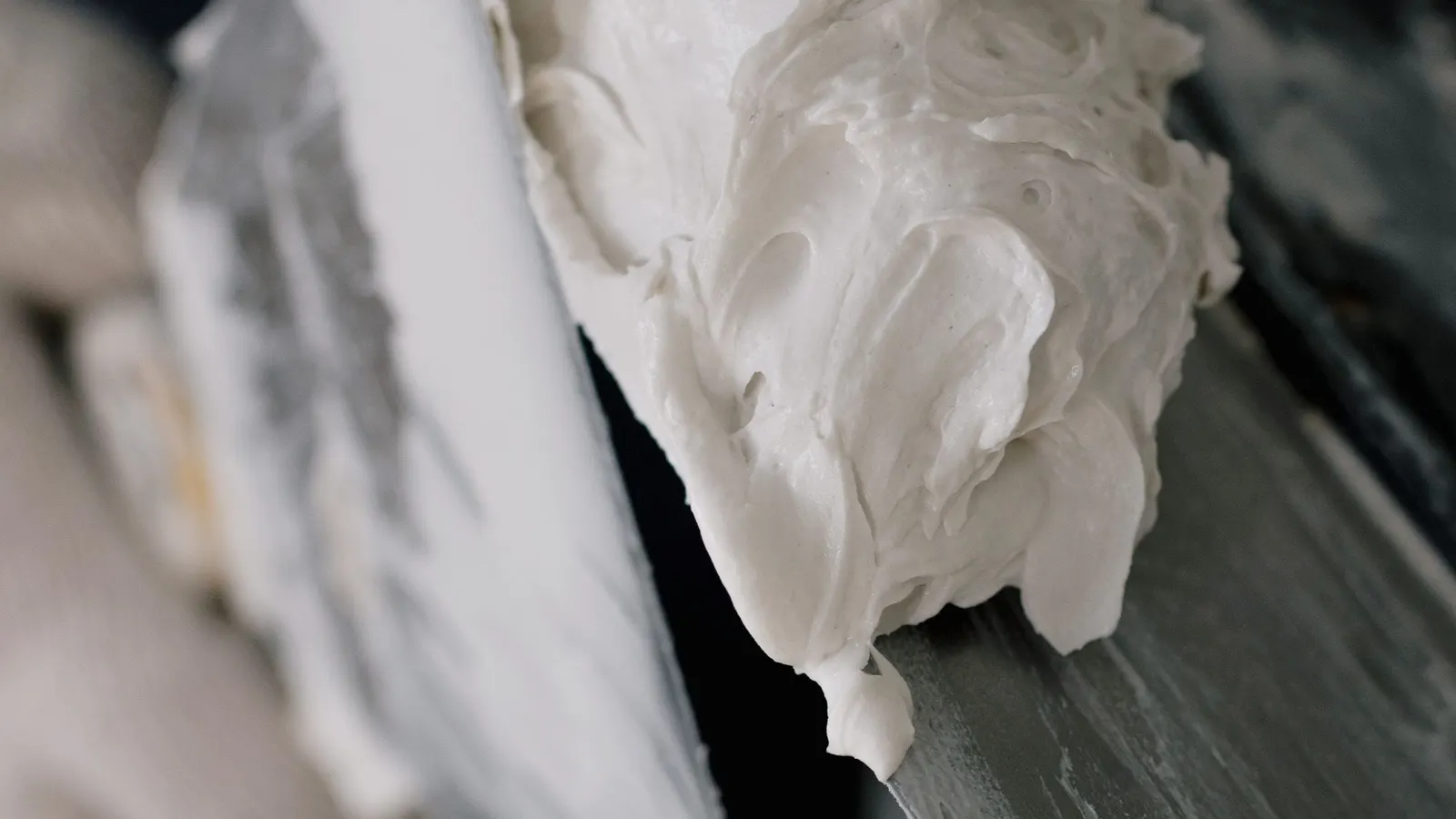 Two putty knives, one loaded with white spackle