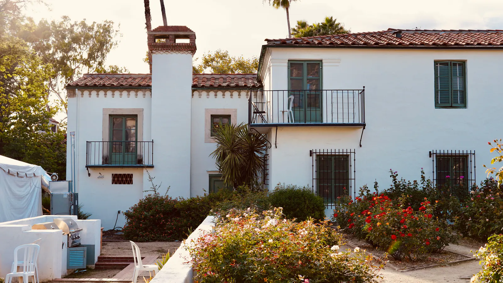 A white stucco house with a tile roof and a garden in front