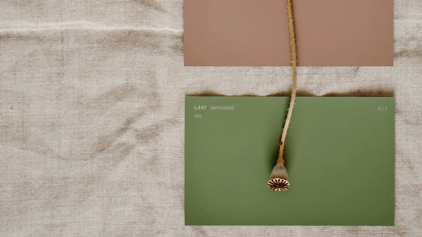 A large green paint sample card and a dusty pink one laid on raw linen
