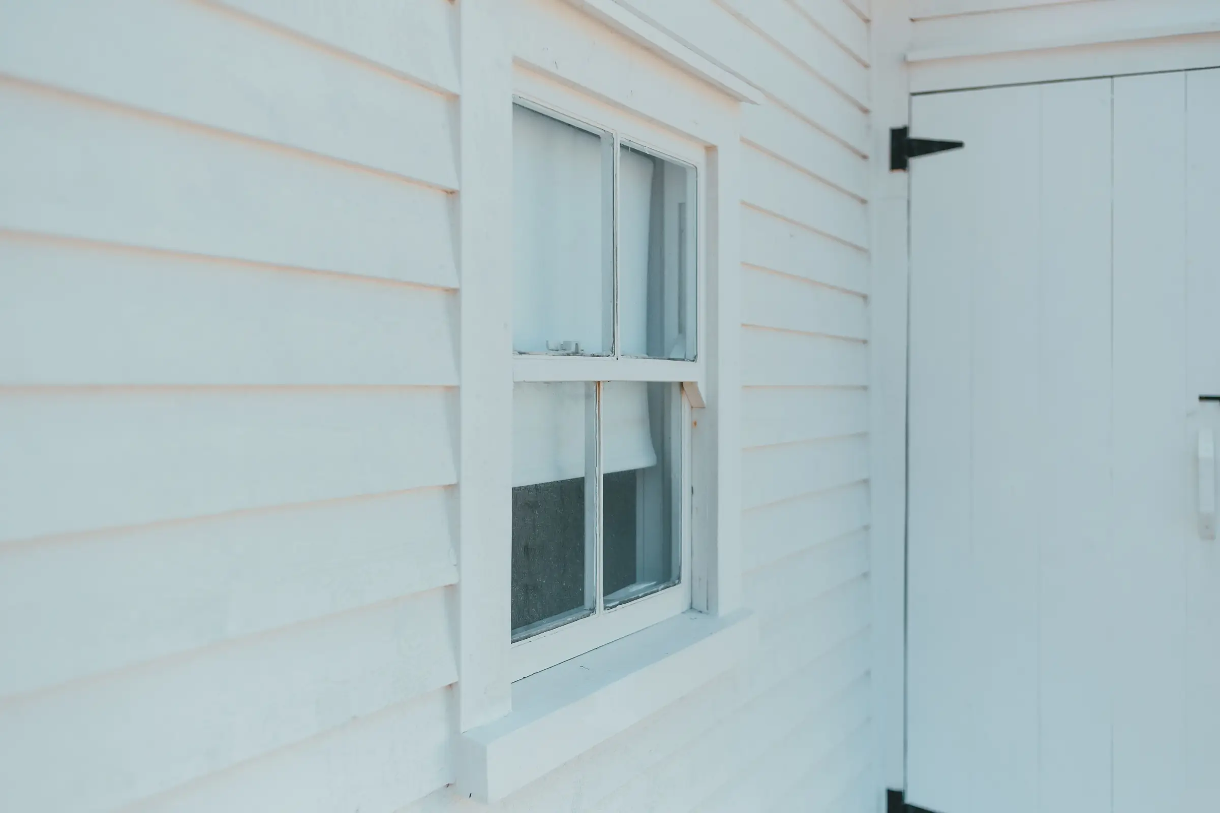White lap siding with a double hung window beside a white door