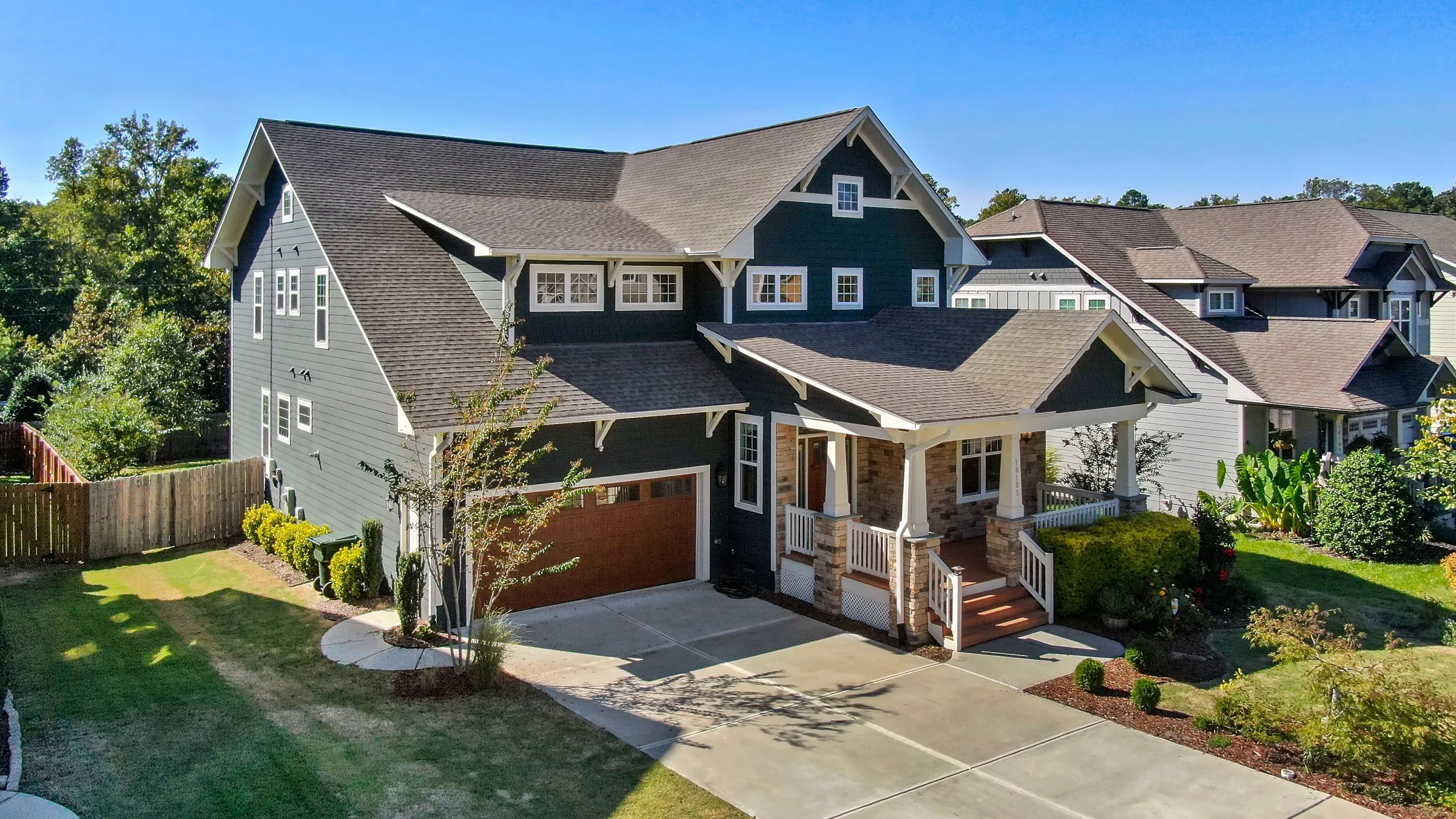 A two-story Craftsman house painted slate blue with white trim and a wood garage door