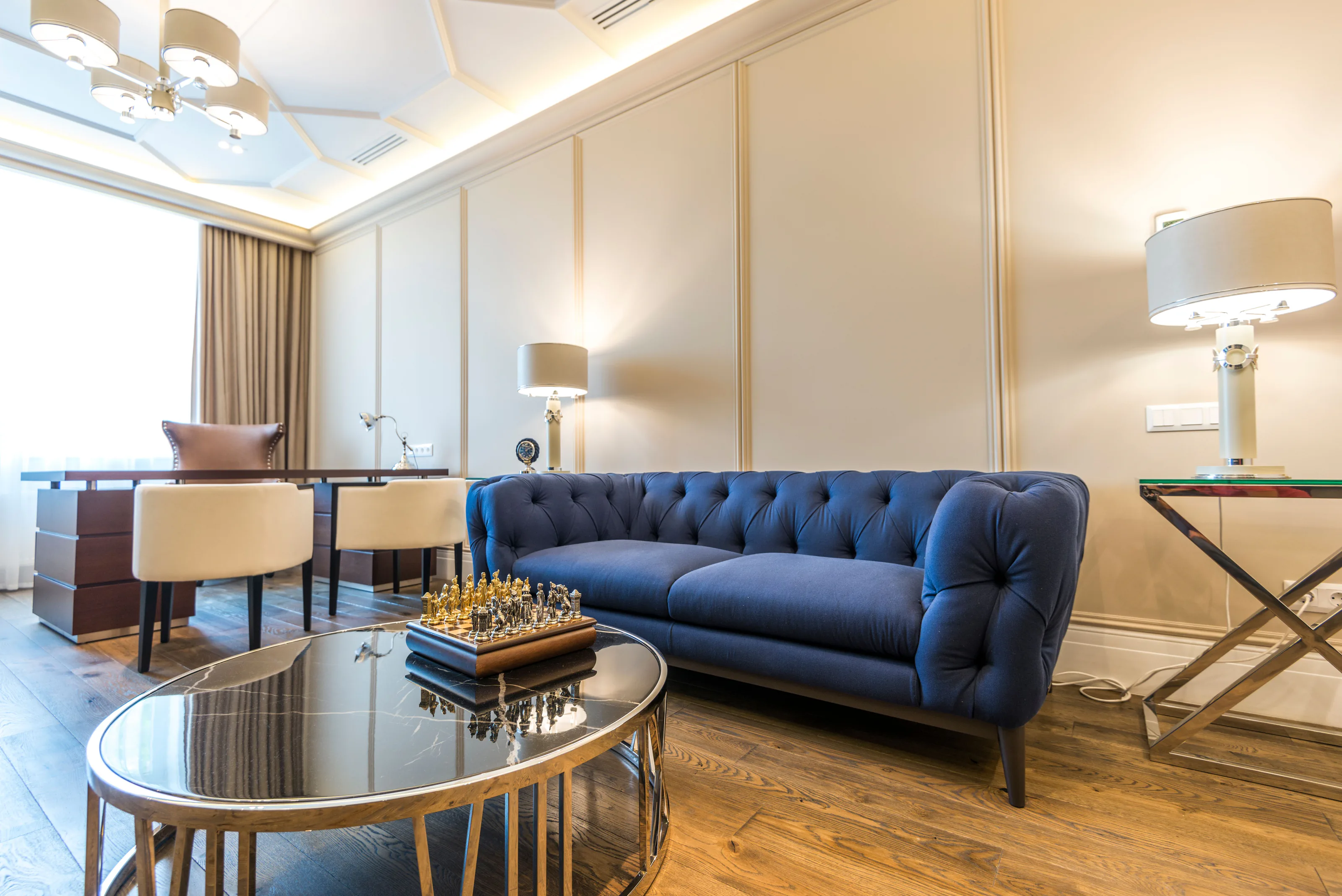 A finished room with cream panelled walls, a navy velvet sofa and brass lamps