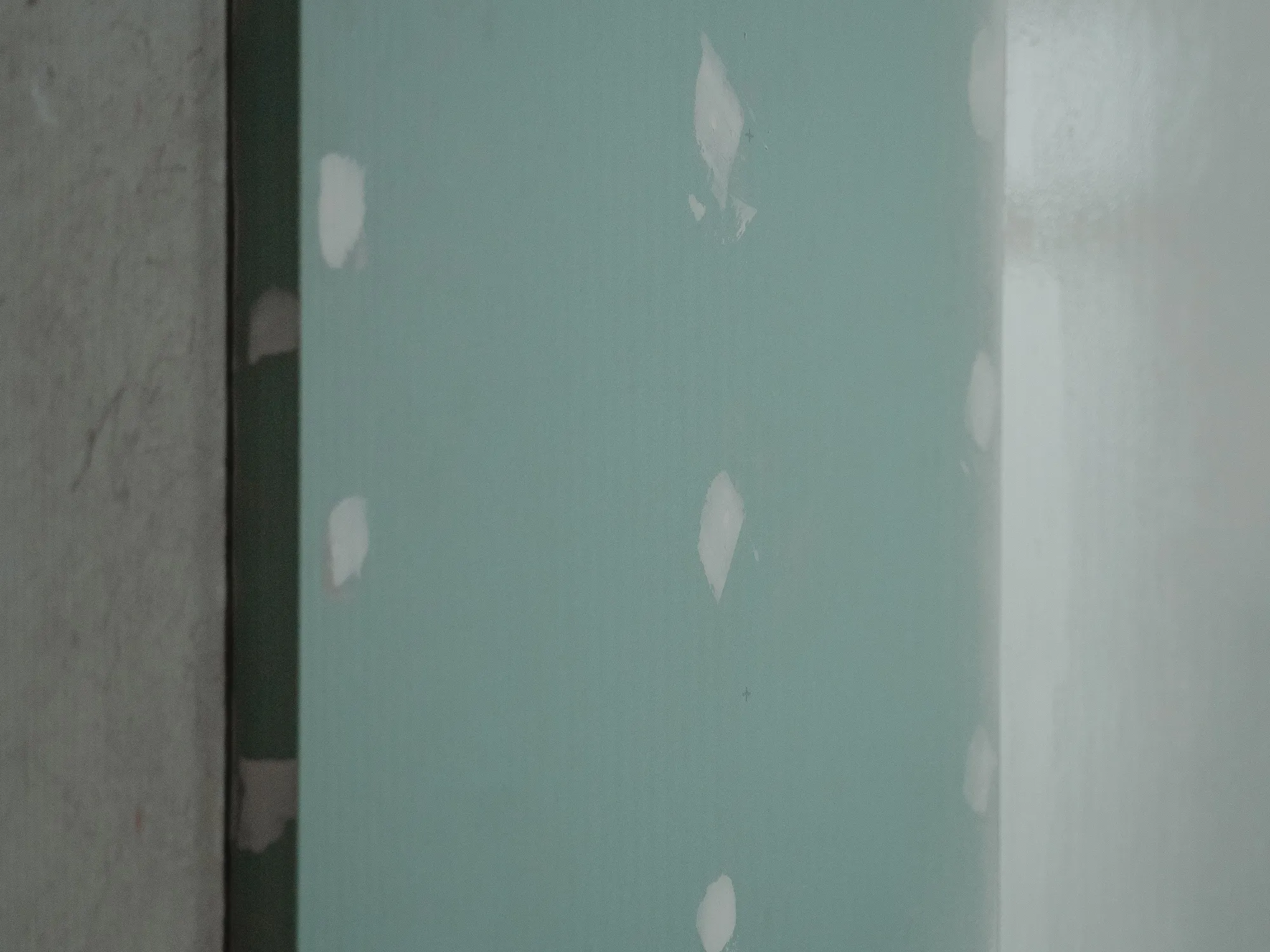 New drywall with its screw holes spotted over in white joint compound