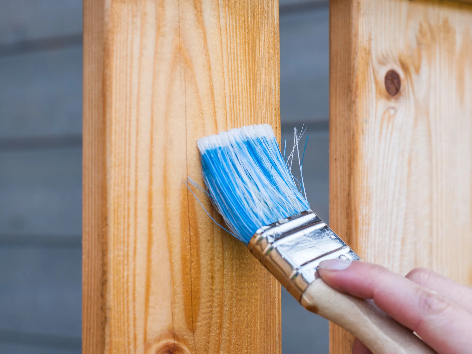 A hand brushing a coat onto pine boards
