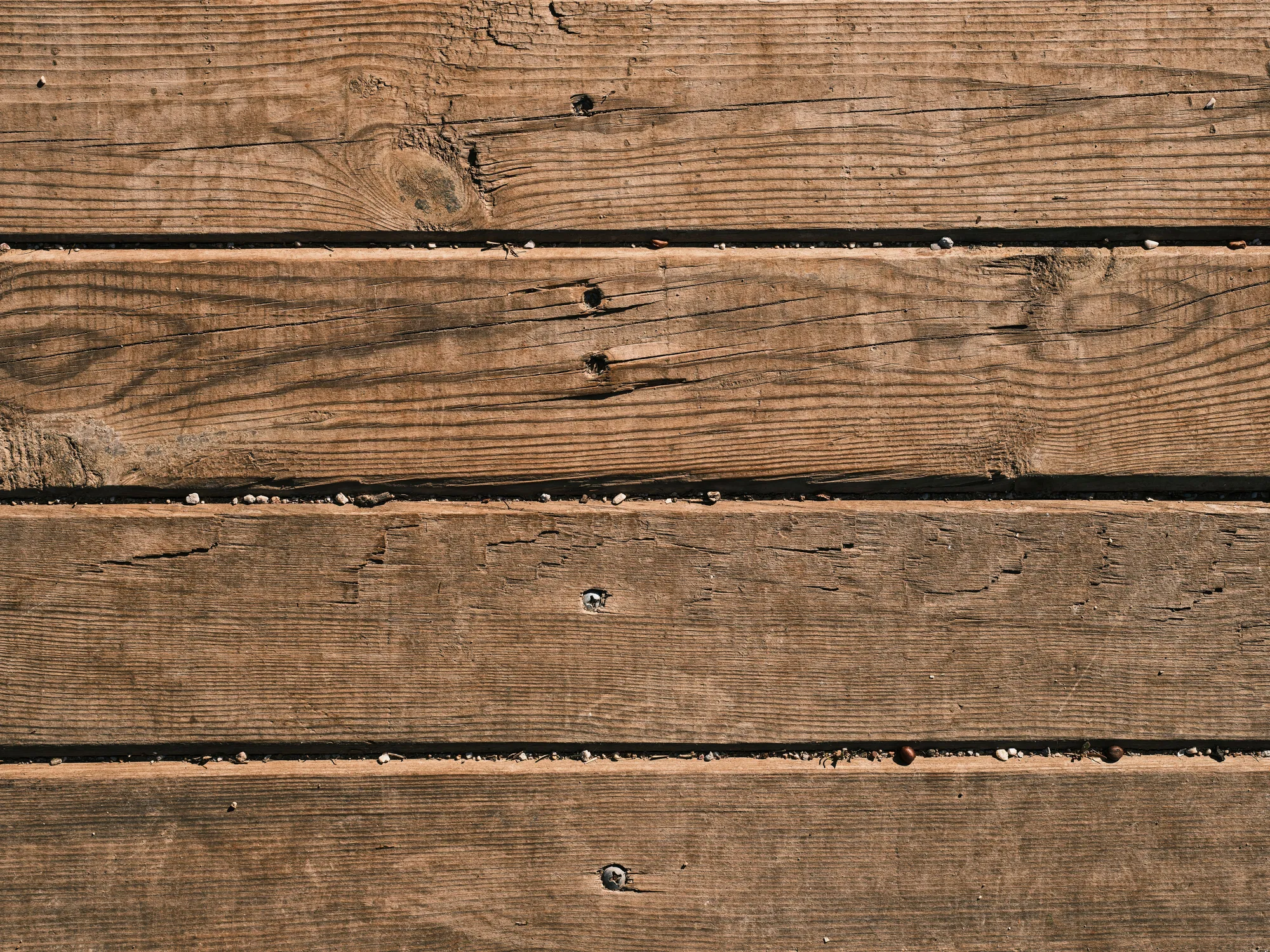 Weathered brown deck boards with exposed nail heads