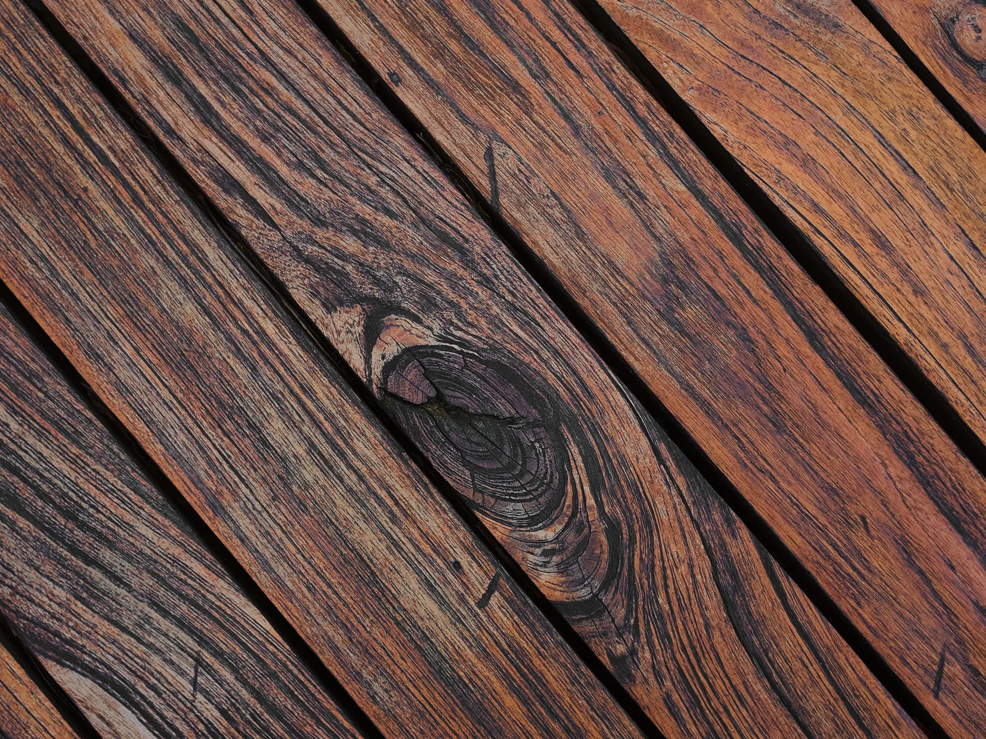 Close-up of weathered brown deck boards with open grain and knots