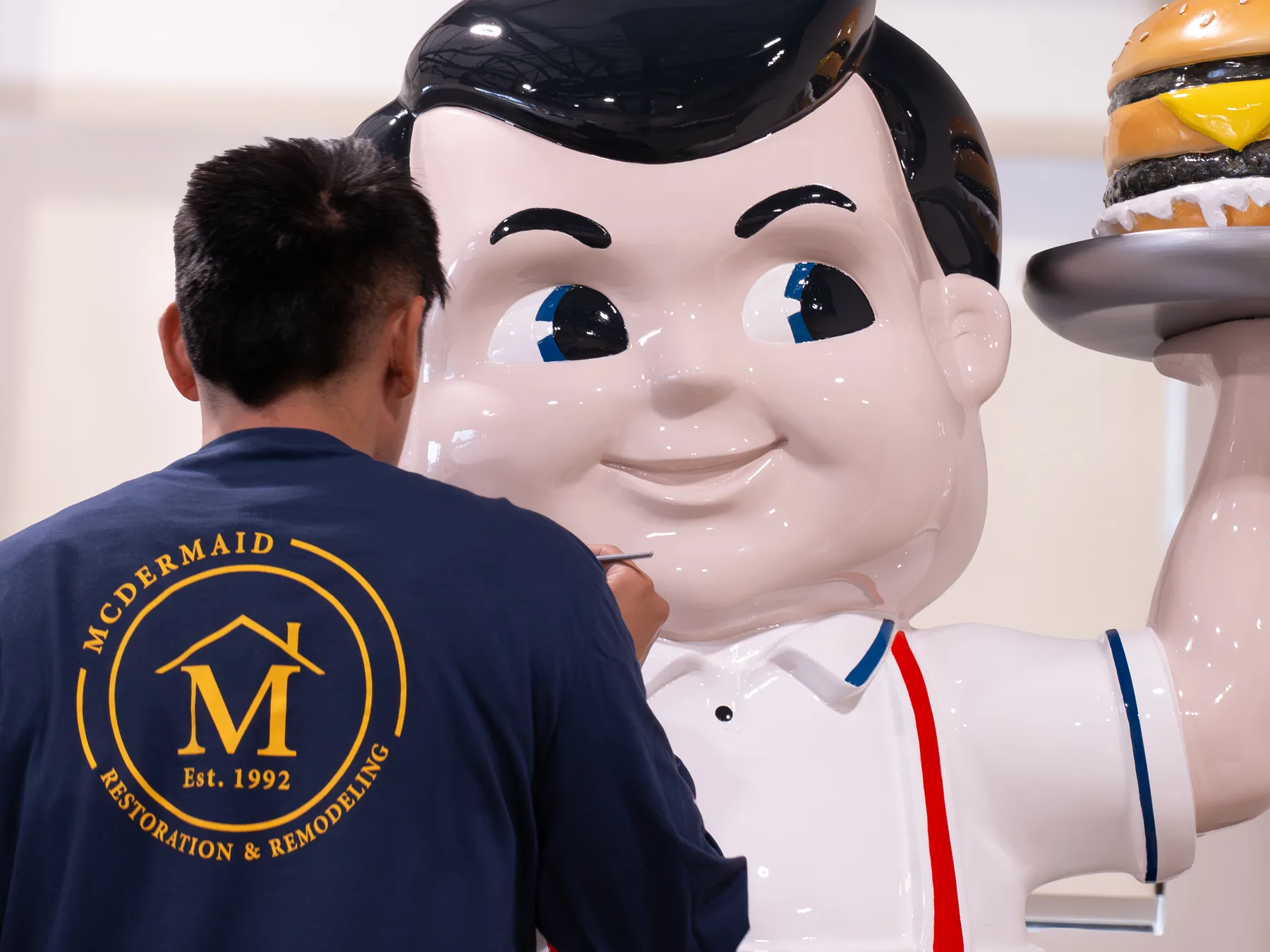 A McDermaid painter in a company sweatshirt detailing the face of the Big Boy statue in the shop