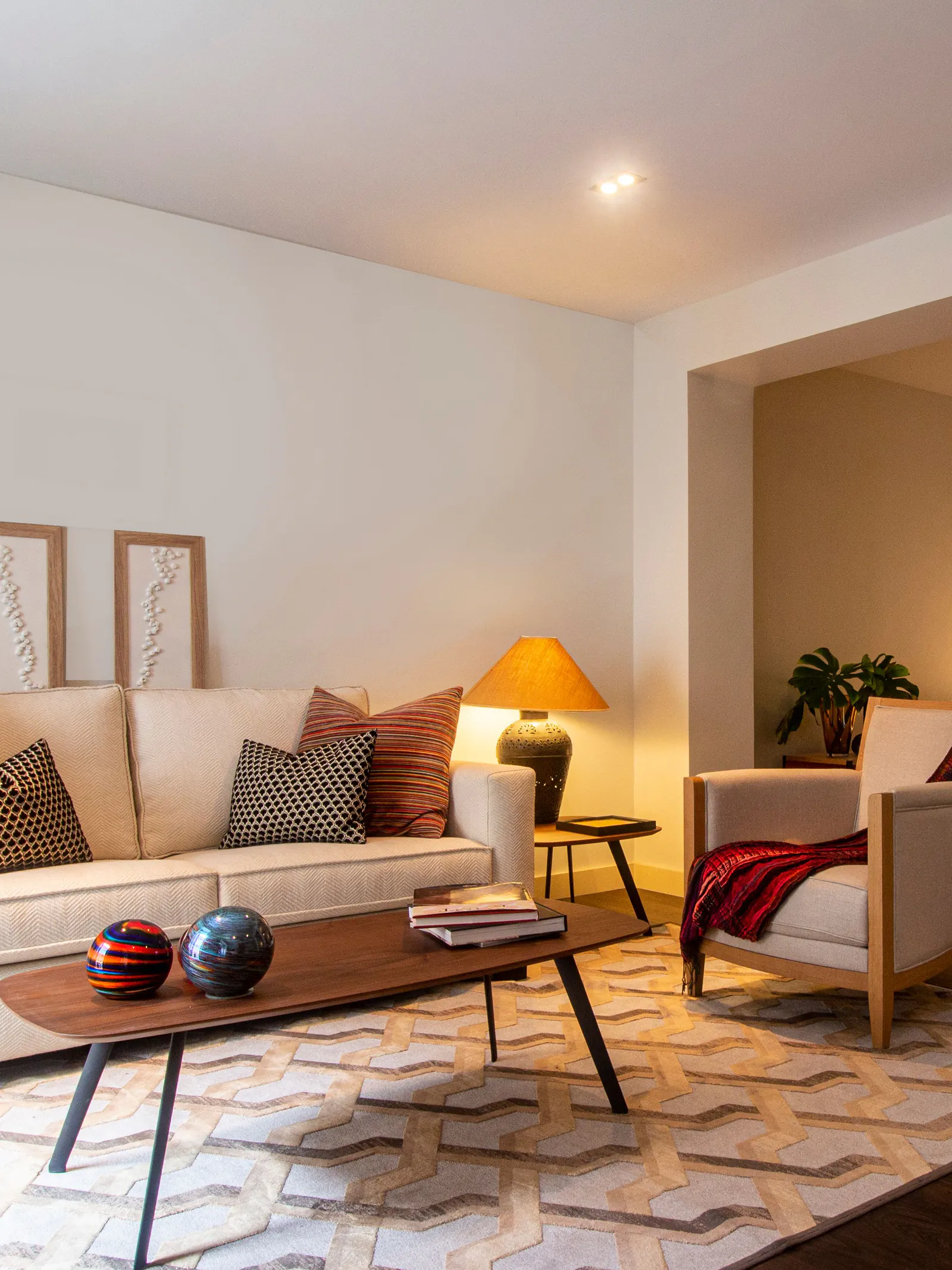 A cream living room with a warm table lamp, striped cushions and a walnut coffee table