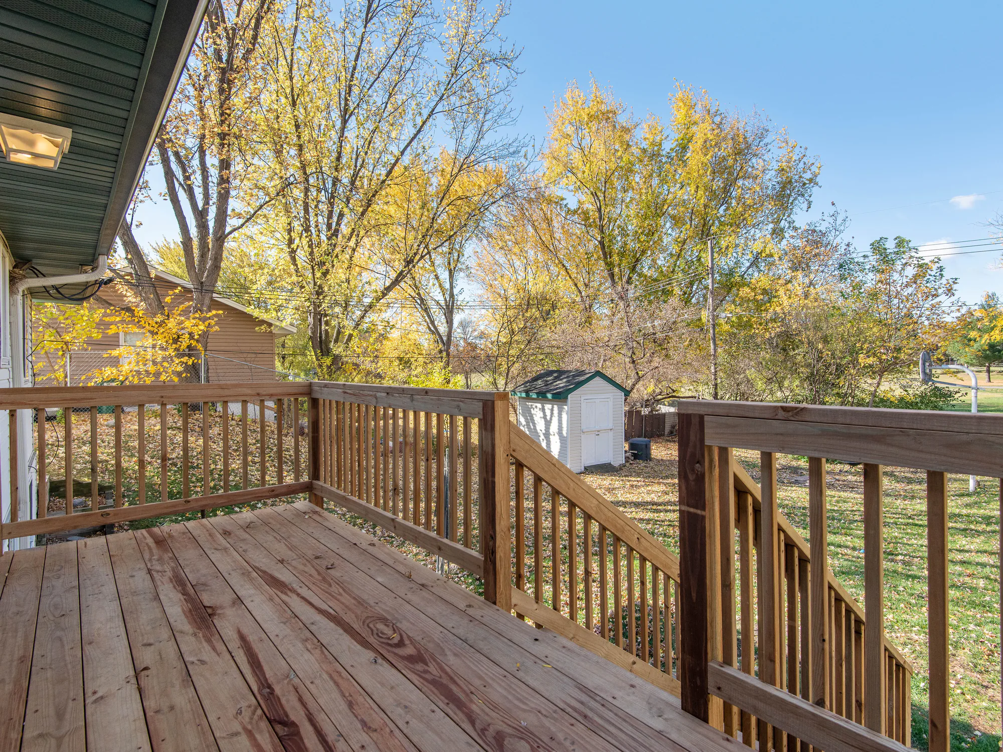 A wooden deck and railing looking out over autumn trees