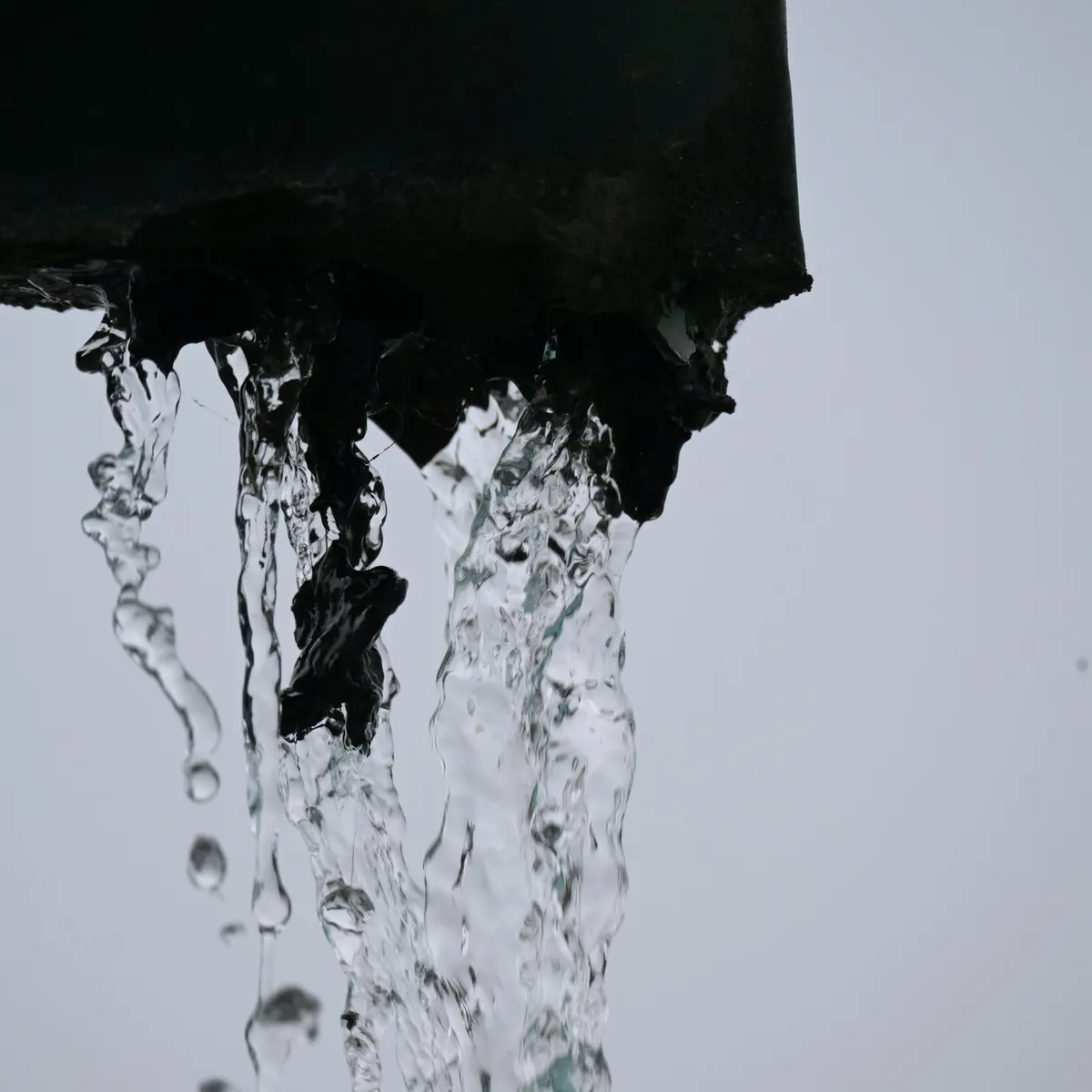 Water pouring off the end of a dark gutter