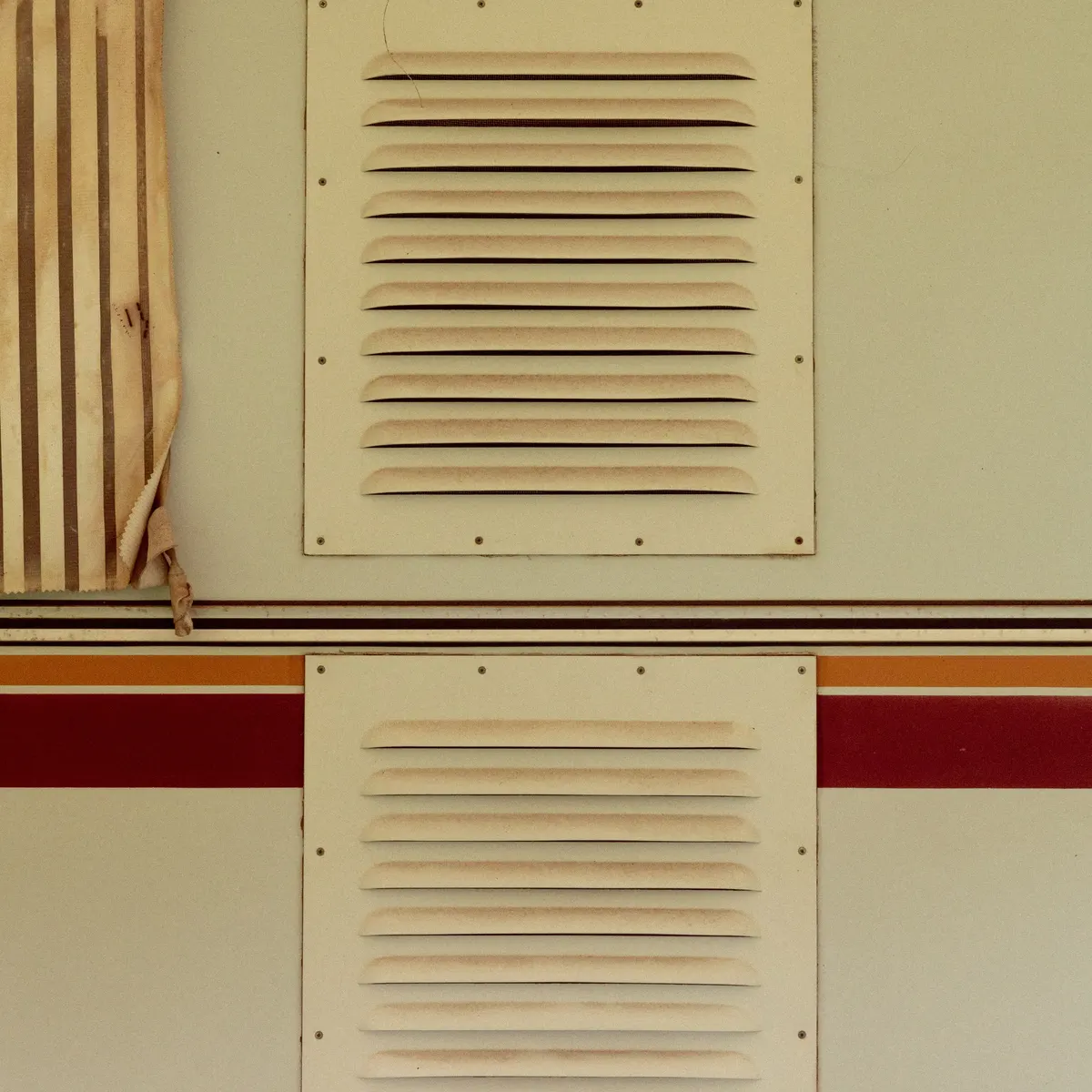 Two louvered vent panels on a cream painted wall