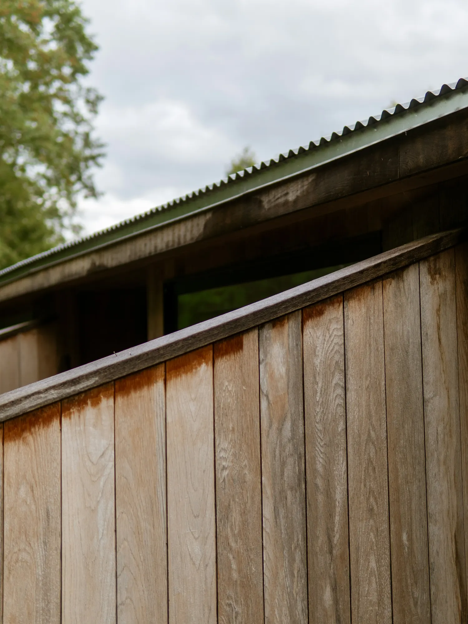 Weathered vertical wood boards under a low metal roof edge