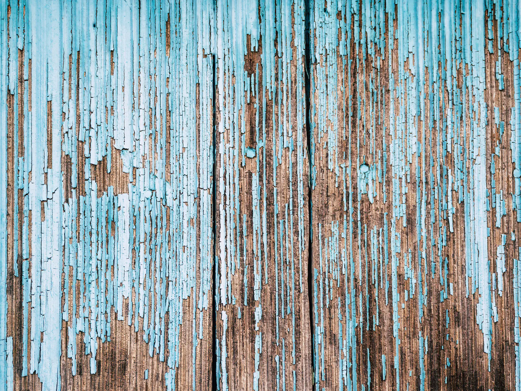 Weathered wooden boards with pale blue paint peeling away to bare wood