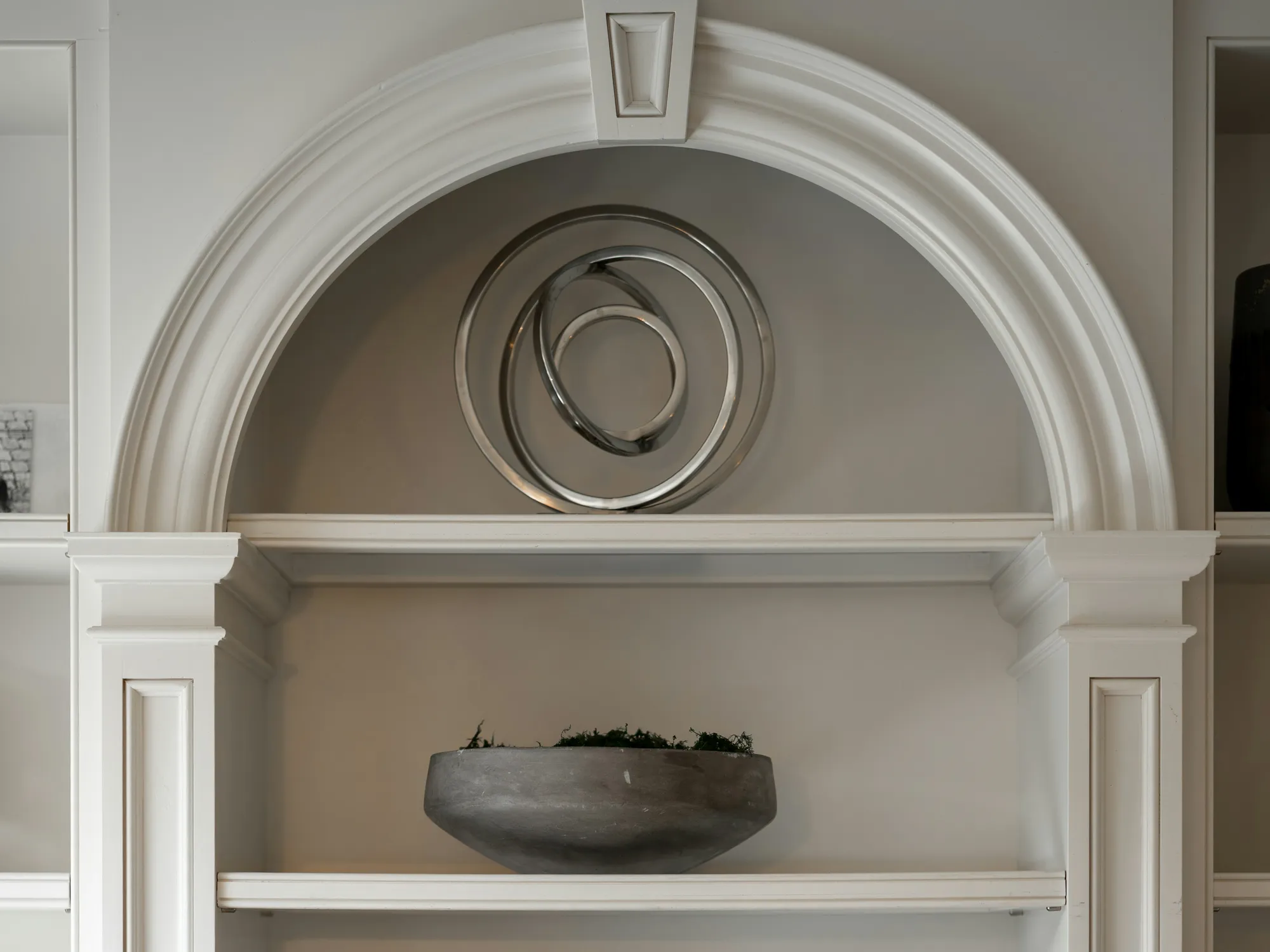 An arched white built-in with fluted pilasters and shelves