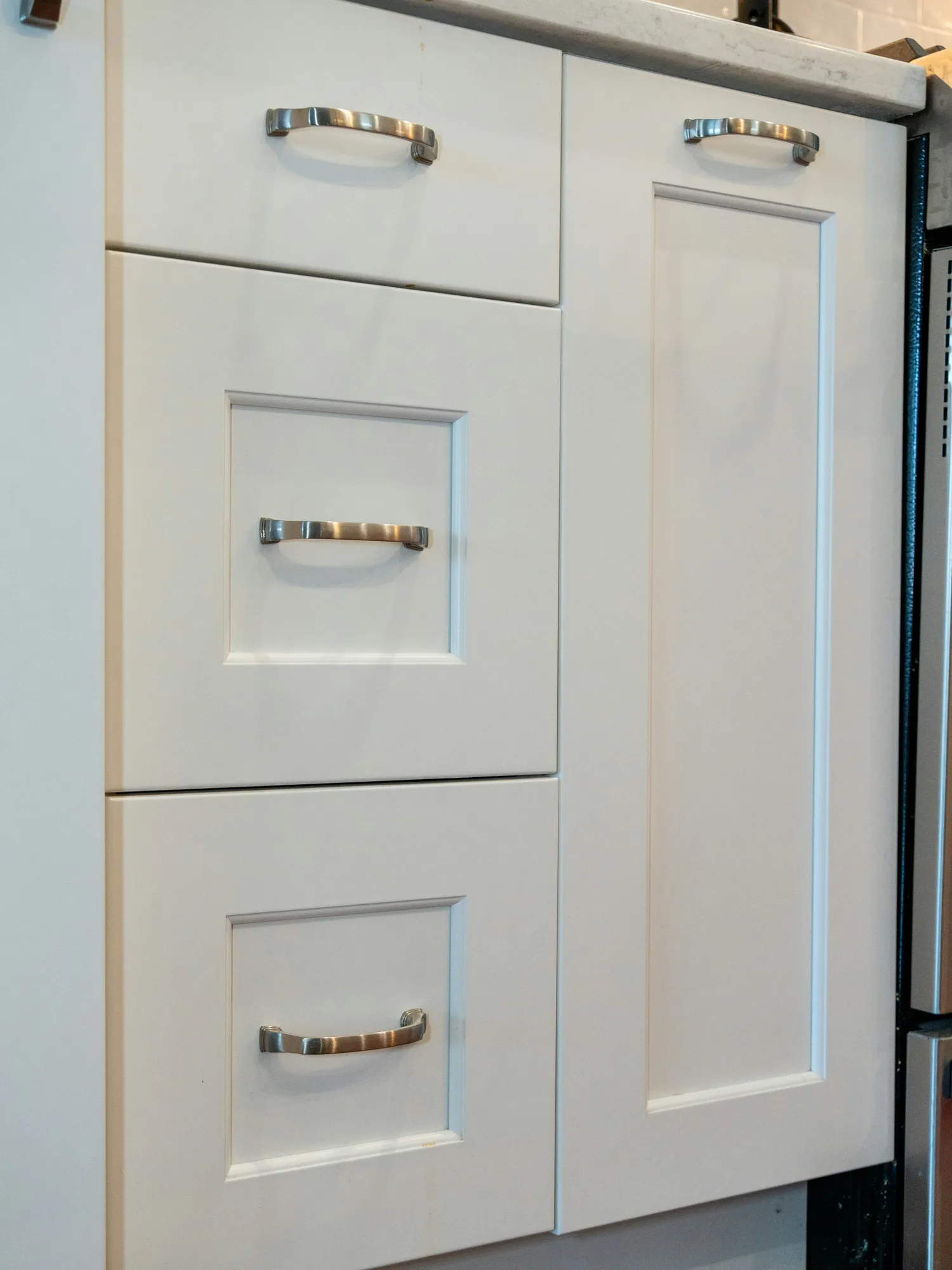 White shaker cabinet drawers with brushed metal pulls